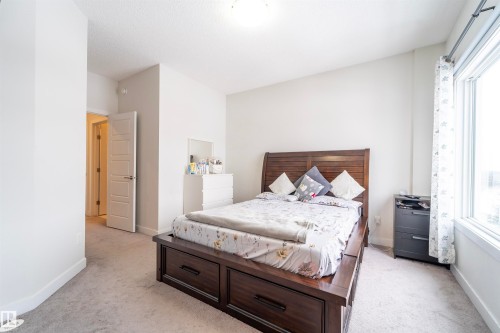 Carpeted bedroom featuring neutral wall paint, a multi-pane window, and a white interior door with panel detailing - 117 804 Welsh Drive, Edmonton, AB - Indoor Photo Showing Bedroom
