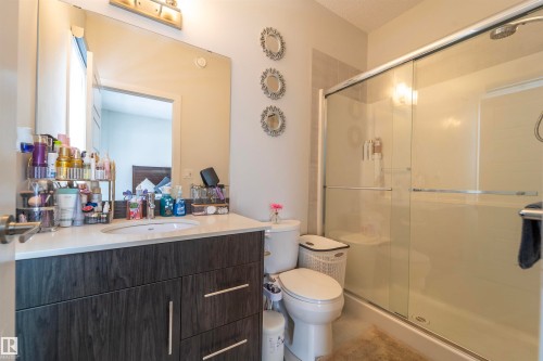 Contemporary bathroom featuring a dark wood-finish vanity with a white countertop and undermount sink, illuminated by a vanity light fixture - 117 804 Welsh Drive, Edmonton, AB - Indoor Photo Showing Bathroom