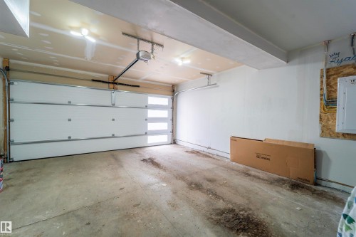 Garage featuring a white sectional door with horizontal frosted glass panels, an automatic opener, concrete flooring, and overhead lighting - 117 804 Welsh Drive, Edmonton, AB - Indoor Photo Showing Garage