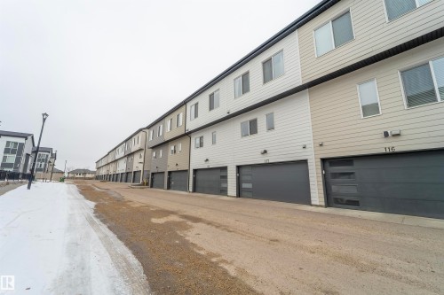 Contemporary townhome residences featuring multi-tone siding and modern garage doors with frosted glass panels - 117 804 Welsh Drive, Edmonton, AB - Outdoor With Exterior