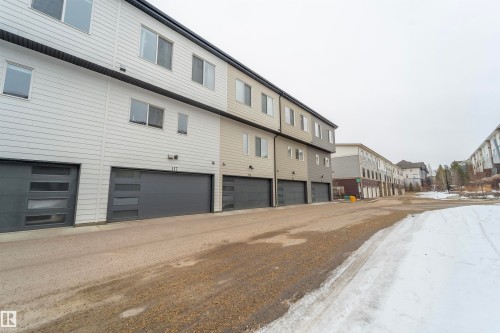 Modern multi-level townhome featuring a neutral exterior siding and attached garage with frosted-panel windows - 117 804 Welsh Drive, Edmonton, AB - Outdoor With Exterior