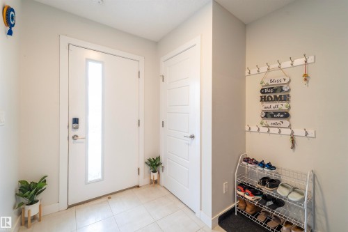 Foyer featuring a white entry door with a vertical frosted glass insert, neutral tile flooring, and light-colored walls - 117 804 Welsh Drive, Edmonton, AB - Indoor Photo Showing Other Room