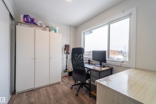 Bright room featuring a large window, wood-finish flooring, white walls, and a built-in closet with sliding doors - 117 804 Welsh Drive, Edmonton, AB - Indoor Photo Showing Office