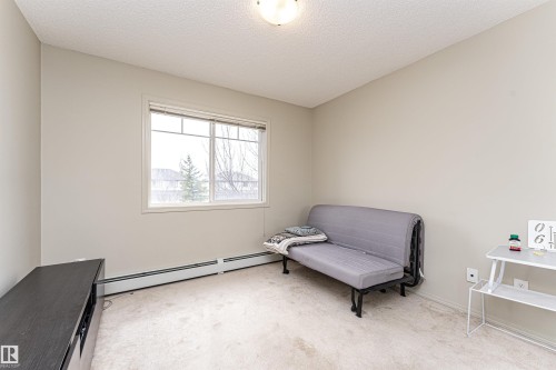 Neutral-toned room featuring a large window with white trim, wall-to-wall carpeting, and baseboard heating - 219 646 Mcallister Loop, Edmonton, AB - Indoor