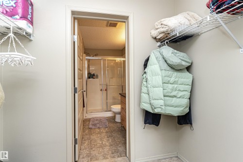 Compact bathroom featuring a glass-enclosed shower, toilet, and vanity with built-in storage - 219 646 Mcallister Loop, Edmonton, AB - Indoor Photo Showing Bathroom