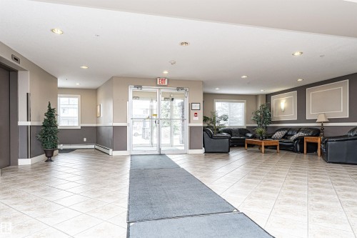 Spacious common area featuring light-toned square tile flooring, recessed ceiling lighting, and a neutral color palette - 219 646 Mcallister Loop, Edmonton, AB - Indoor