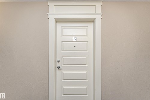 Crisp white six-panel door with decorative trim and brushed nickel hardware - 219 646 Mcallister Loop, Edmonton, AB -  Photo Showing Other Room