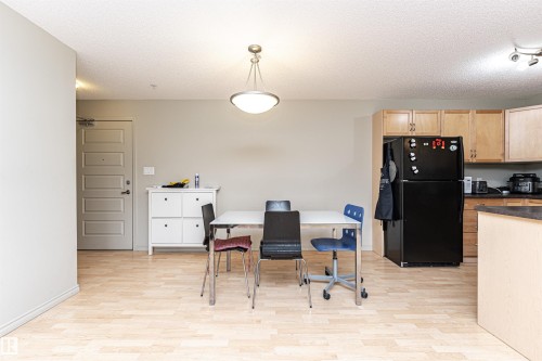 Open-concept living space featuring wood-finish flooring, a contemporary pendant light fixture, and neutral wall tones - 219 646 Mcallister Loop, Edmonton, AB - Indoor Photo Showing Kitchen