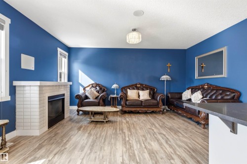 Spacious living area featuring wood-finish flooring, a tiled fireplace, and multiple windows - 9812 224 Street, Edmonton, AB - Indoor Photo Showing Living Room With Fireplace