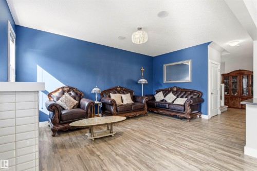 Spacious living area featuring wood-finish flooring, a vibrant accent wall, white baseboards, and ceiling-mounted light fixtures - 9812 224 Street, Edmonton, AB - Indoor Photo Showing Living Room