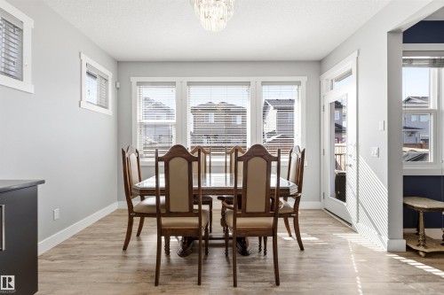 Dining area featuring wood-finish flooring, white trim, and a glass-paneled exterior door - 9812 224 Street, Edmonton, AB - Indoor Photo Showing Dining Room