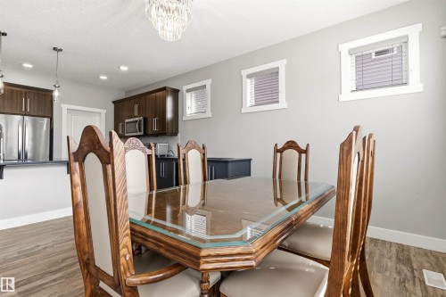 Open-concept dining area featuring a crystal chandelier and wood-finish flooring - 9812 224 Street, Edmonton, AB - Indoor Photo Showing Dining Room