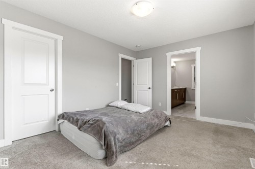 Carpeted bedroom featuring light gray walls, white baseboards, and white trim around a paneled door - 9812 224 Street, Edmonton, AB - Indoor Photo Showing Bedroom