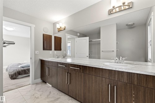 Bathroom vanity with dual sinks, a stone-finish countertop, and rich wood-finish cabinetry - 9812 224 Street, Edmonton, AB - Indoor Photo Showing Bathroom