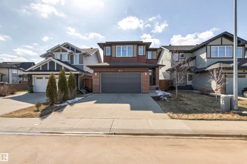 Contemporary home exterior featuring a brick facade, dark wood-tone siding, and a dark garage door - 9812 224 Street, Edmonton, AB - Outdoor With Facade