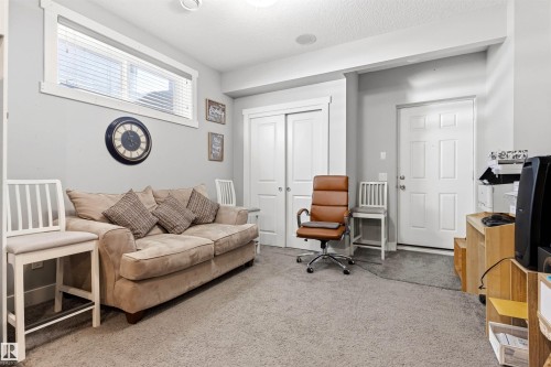 Carpeted room featuring light gray walls, a high horizontal window with white trim, a white six-panel door, and white bi-fold closet doors - 9812 224 Street, Edmonton, AB - Indoor