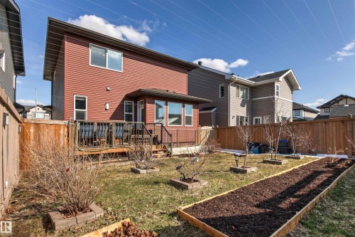 Rear exterior featuring a wood deck, red horizontal siding, and multiple windows - 9812 224 Street, Edmonton, AB - Outdoor With Deck Patio Veranda