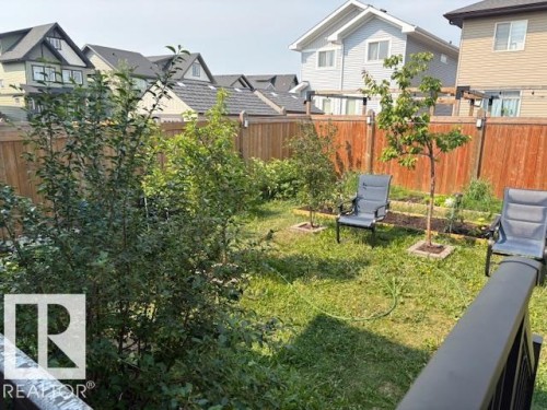 Fenced backyard space featuring established trees, planting beds with mulch, and a grassy area - 9812 224 Street, Edmonton, AB - Outdoor