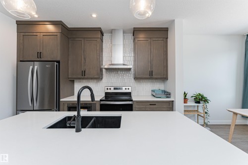 Kitchen featuring a large central island with an undermount sink and matte black faucet - 3367 Erlanger Bend, Edmonton, AB - Indoor Photo Showing Kitchen With Upgraded Kitchen