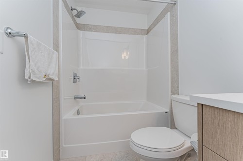 White acrylic tub and shower combination with chrome fixtures, bordered by a tiled accent - 3367 Erlanger Bend, Edmonton, AB - Indoor Photo Showing Bathroom