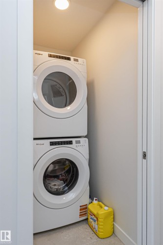 Dedicated laundry closet featuring a stacked white front-load washer and dryer set, recessed ceiling lighting, and light-toned flooring - 3367 Erlanger Bend, Edmonton, AB - Indoor Photo Showing Laundry Room