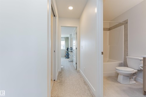 Bathroom featuring a white bathtub, tiled shower surround with a light grey accent band, and a white toilet - 3367 Erlanger Bend, Edmonton, AB - Indoor Photo Showing Bathroom