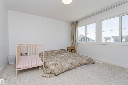 Light-filled interior space featuring two large windows with white frames, neutral-toned curtains, and light-colored carpeting - 3367 Erlanger Bend, Edmonton, AB - Indoor Photo Showing Bedroom