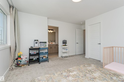 Spacious carpeted room featuring a window with natural light, a recessed ceiling light, and white paneled doors - 3367 Erlanger Bend, Edmonton, AB - Indoor