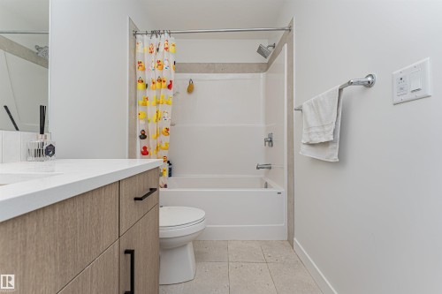 Bathroom featuring a white bathtub and shower combination, a light wood-finish vanity with a white countertop, and light-toned floor tiling - 3367 Erlanger Bend, Edmonton, AB - Indoor Photo Showing Bathroom