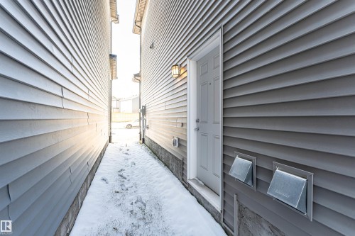 Gray horizontal siding exterior with white trim around a paneled entry door - 3367 Erlanger Bend, Edmonton, AB - Outdoor With Exterior