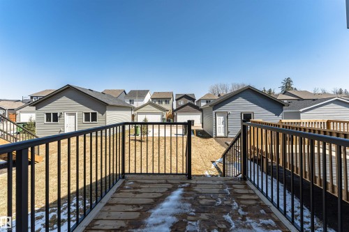 Rear deck with a wood surface and black metal railings, overlooking a sloped yard - 3367 Erlanger Bend, Edmonton, AB - Outdoor