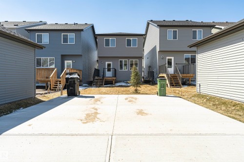 Rear exterior featuring a concrete pad, a wooden deck with dark railings, and a white exterior door - 3367 Erlanger Bend, Edmonton, AB - Outdoor