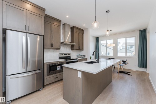 Kitchen featuring light wood-finish flooring, recessed lighting, and a kitchen island with an undermount sink and matte black faucet - 3367 Erlanger Bend, Edmonton, AB - Indoor Photo Showing Kitchen With Upgraded Kitchen