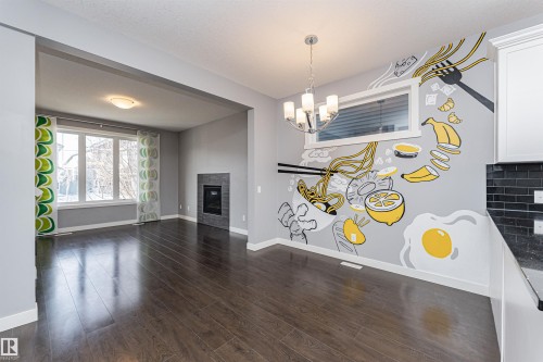 Open-concept living area featuring rich wood-finish flooring, a contemporary chandelier, and a unique wall mural - 16420 15 Avenue, Edmonton, AB - Indoor With Fireplace