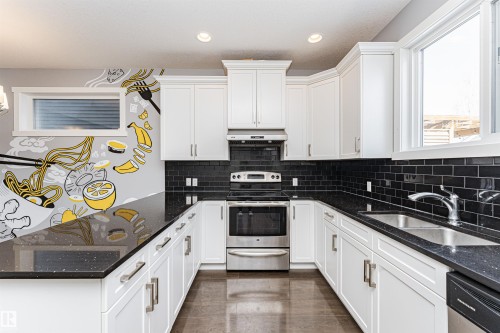 Modern kitchen featuring white shaker cabinetry, black subway tile backsplash, dark speckled countertops, and stainless steel appliances - 16420 15 Avenue, Edmonton, AB - Indoor Photo Showing Kitchen With Upgraded Kitchen