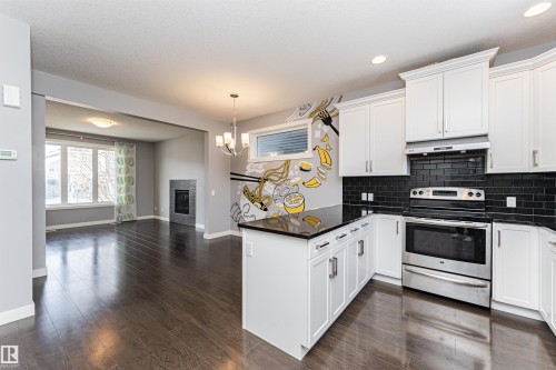 Modern kitchen featuring white cabinetry, black subway tile backsplash, and a central island with a dark countertop - 16420 15 Avenue, Edmonton, AB - Indoor Photo Showing Kitchen