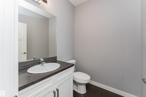 Vanity area featuring an oval under-mount sink, dark countertop, and brushed nickel faucet - 16420 15 Avenue, Edmonton, AB - Indoor Photo Showing Bathroom