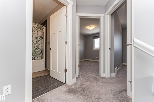 Hallway featuring light gray carpeting, white trim, and doors - 16420 15 Avenue, Edmonton, AB - Indoor Photo Showing Other Room