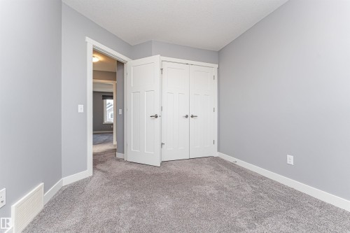 Spacious room with plush gray carpet, light gray wall paint, and crisp white baseboards - 16420 15 Avenue, Edmonton, AB - Indoor Photo Showing Other Room