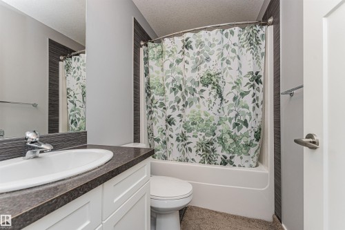 White bathtub and shower combination with a curved shower rod - 16420 15 Avenue, Edmonton, AB - Indoor Photo Showing Bathroom