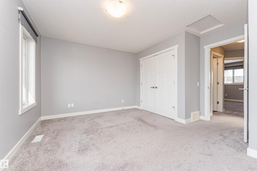 Spacious room featuring light grey carpeting, white baseboards, a flush-mount ceiling light fixture, and a window with a roller shade - 16420 15 Avenue, Edmonton, AB - Indoor Photo Showing Other Room
