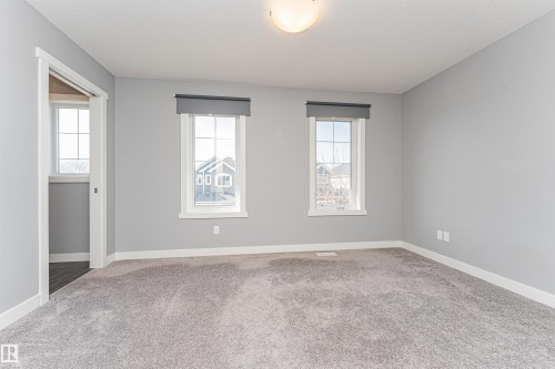 Carpeted interior space featuring two large windows with roller shades, white trim, and a semi-flush mount ceiling light - 16420 15 Avenue, Edmonton, AB - Indoor Photo Showing Other Room