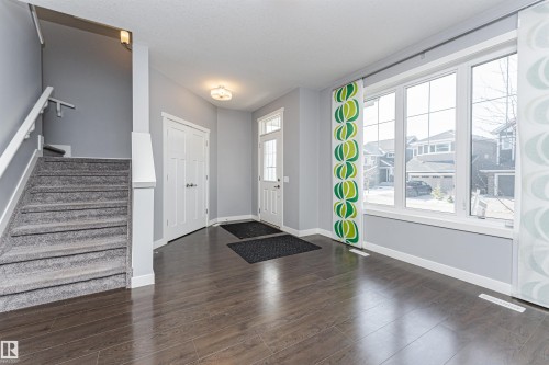 Entryway featuring rich wood-finish flooring, a multi-pane glass door, and a carpeted staircase with a white railing - 16420 15 Avenue, Edmonton, AB - Indoor Photo Showing Other Room