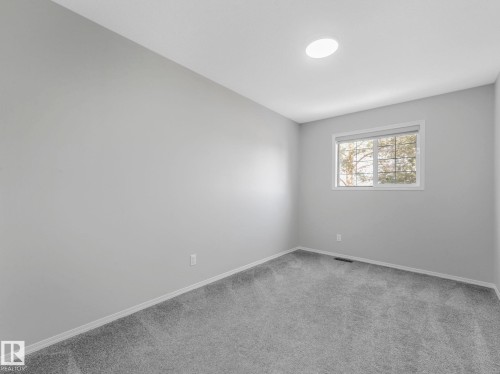 This room features light grey carpeting, white trim, and a window with a view of trees - 175 150 Edwards Drive, Edmonton, AB - Indoor Photo Showing Other Room
