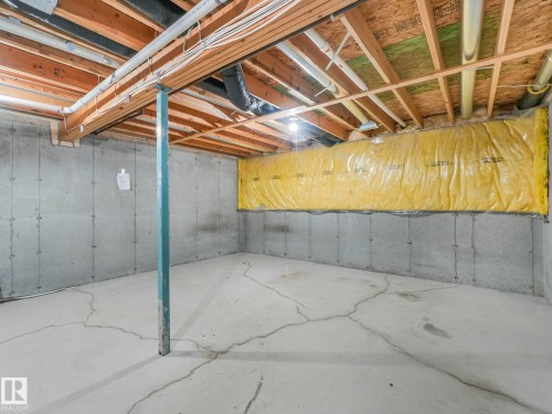 Unfinished space with exposed ceiling joists and concrete walls, offering potential for customization - 175 150 Edwards Drive, Edmonton, AB - Indoor Photo Showing Basement