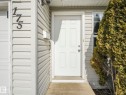 The property features light-colored horizontal siding, a white front door with paneling, and an overhead light fixture - 175 150 Edwards Drive, Edmonton, AB  - Outdoor With Exterior 