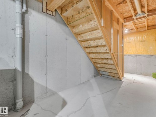 The property features a utility area with exposed concrete walls, a wooden staircase, and an insulated wall section - 175 150 Edwards Drive, Edmonton, AB - Indoor
