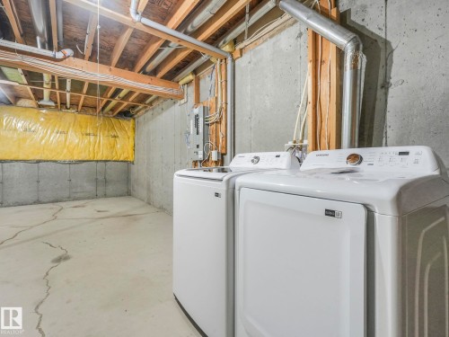The property includes a utility area with concrete walls and exposed wooden ceiling beams - 175 150 Edwards Drive, Edmonton, AB - Indoor Photo Showing Laundry Room