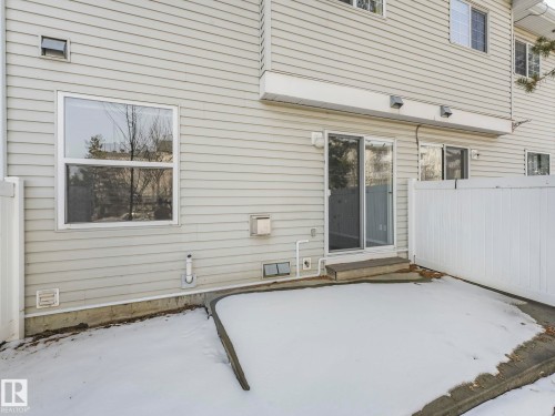 The property features light-colored horizontal siding, a private patio, and sliding glass doors - 175 150 Edwards Drive, Edmonton, AB - Outdoor With Exterior