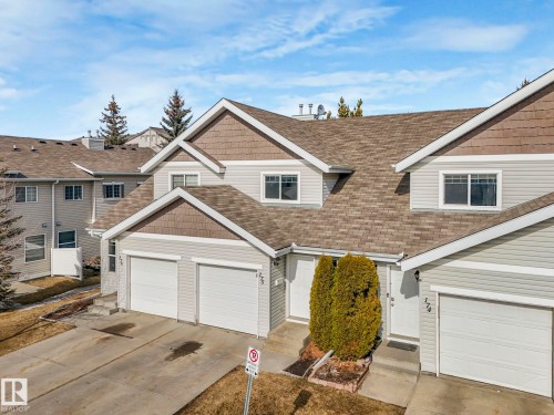 The property features a multi-level roofline, light grey siding with brown shake accents, and white trim - 175 150 Edwards Drive, Edmonton, AB - Outdoor